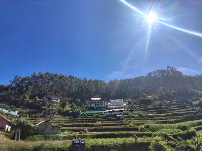 a sun shines over a village on a mountain at Kalpanahomestay in Vattavada