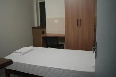 a bedroom with a bed and a wooden cabinet at Jo Homes in Alwaye