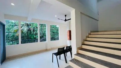 a staircase in a house with two chairs and windows at Jo Homes in Alwaye