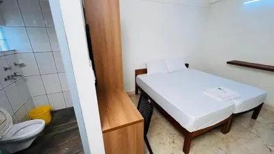 a small room with a bed and a shower and a toilet at Jo Homes in Alwaye