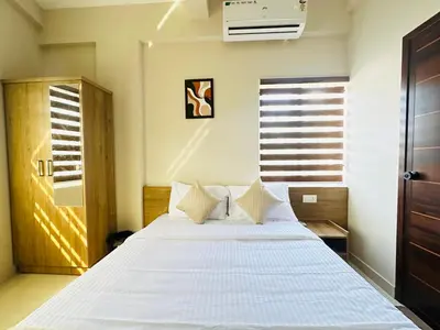 a bedroom with a large bed with white sheets at Nila Inn Calicut Near Hilite Mall in Kozhikode