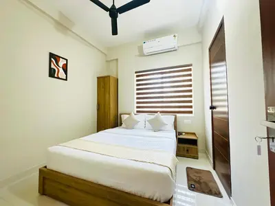 a bedroom with a bed with white sheets and a window at Nila Inn Calicut Near Hilite Mall in Kozhikode