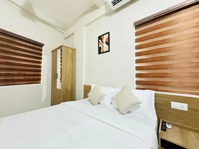 a bedroom with a bed and a wooden headboard at Nila Inn Calicut Near Hilite Mall in Kozhikode