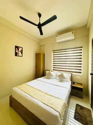 a bedroom with a large bed with a ceiling fan at Nila Inn Calicut Near Hilite Mall in Kozhikode