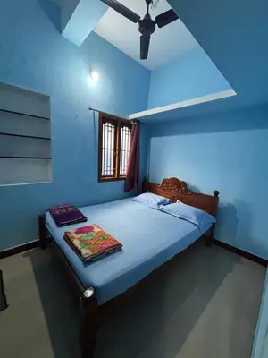 a bedroom with a bed in a blue room at Park view homestays in Vālpārai
