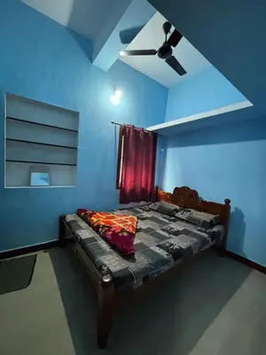 a bedroom with a bed with a ceiling fan at Park view homestays in Vālpārai