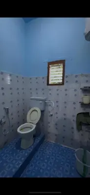 a bathroom with a toilet and a window in it at Park view homestays in Vālpārai