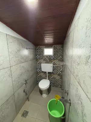 a bathroom with a toilet and a green bucket at Park view homestays in Vālpārai