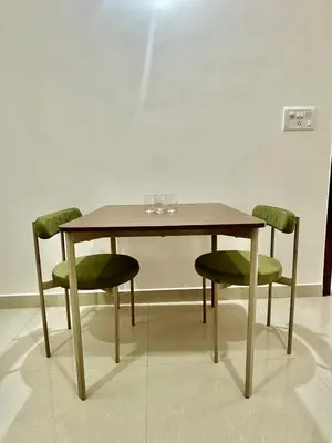 a wooden table with chairs and glasses on it at Dakshima Residency in Mysore