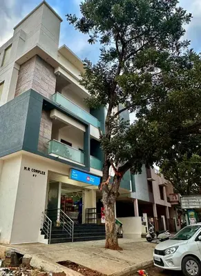 a building with a tree in front of it at Dakshima Residency in Mysore