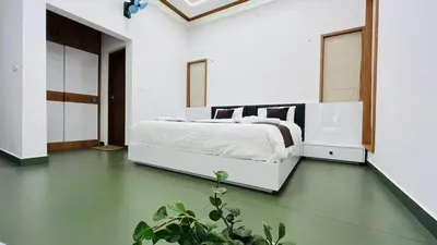 a bedroom with a white bed and a green floor at Mistora Stays 2BHK Private villa in Kalpetta