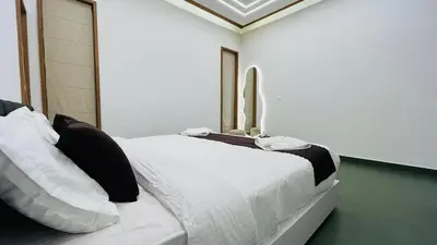 a bedroom with a white bed with black and white pillows at Mistora Stays 2BHK Private villa in Kalpetta