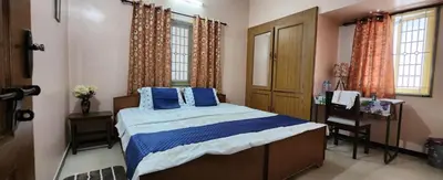 a bedroom with a bed with blue pillows and a desk at Deepam Homestay in Coimbatore