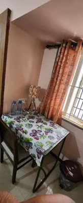 a table with a blanket on it in front of a window at Deepam Homestay in Coimbatore