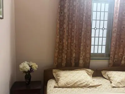 a bedroom with a bed and a window with a vase of flowers at Deepam Homestay in Coimbatore
