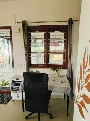 a table and a chair in a room with a window at Āsare attic in Mysore
