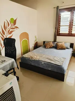 a bedroom with a bed and a chair in it at Āsare attic in Mysore