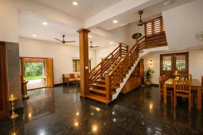 a living room with a staircase and a dining room at Heritage Home in Ernakulam North Paravur in Ernakulam