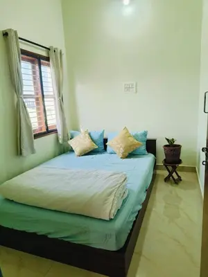 a bedroom with a bed with blue sheets and a window at Aasare Attic 2 in Mysore