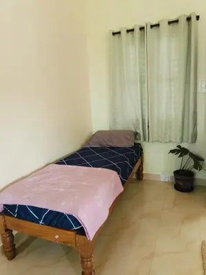 a bedroom with two twin beds and a window at Aasare Attic 2 in Mysore
