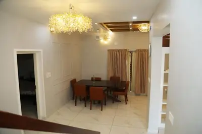 a dining room with a table and chairs and a chandelier at Brand new 4 BHK luxury villa near kochi airport in Nedumbassery