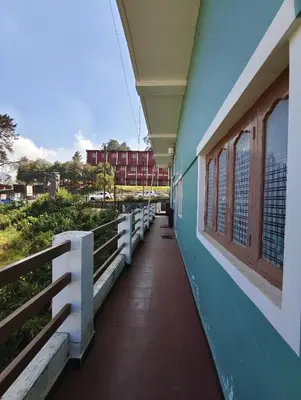 a corridor of a building with a blue wall and windows at KINGS Home Stay in Ooty