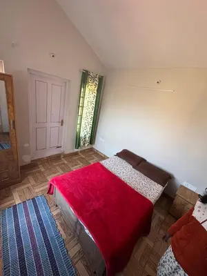 a bedroom with a bed with a red blanket on it at KINGS Home Stay in Ooty