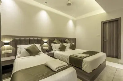 a hotel room with two beds and two lamps at Hotel Hycon in Kozhikode