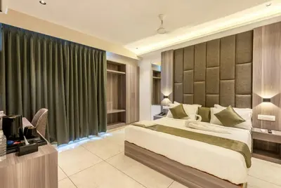 a bedroom with a bed and a desk with a television at Hotel Hycon in Kozhikode