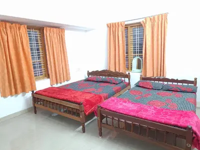 two beds sitting in a room with windows at SoNish Homestay Marayur - 3 bedroom for 25-30 people - Booking will be confirmed only after advance payment in Marayoor