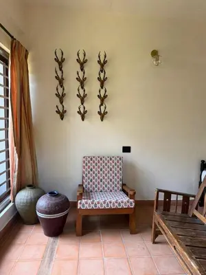 a room with a chair and a vase on a wall at Homestay in Alappura 3 Cottage Farmstay by Homeyhuts in Tattamangalam