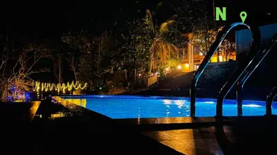an empty swimming pool at night with lights at Nvoyages Wayanad in Wayanad