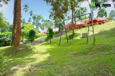 a swing set on a hill with a house in the background at Nvoyages Wayanad in Wayanad