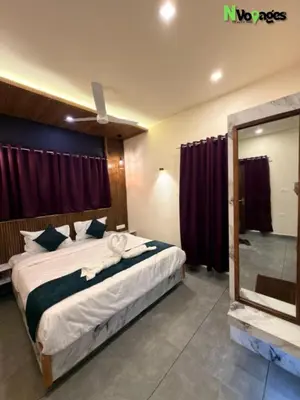 a bedroom with a large bed and a mirror at Nvoyages Wayanad in Wayanad