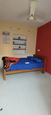 a bedroom with a bed with a blue blanket on it at Yakuhomestay in Vālpārai