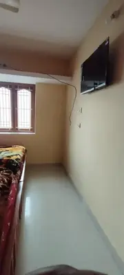 a room with a bed and a tv on a wall at Yakuhomestay in Vālpārai