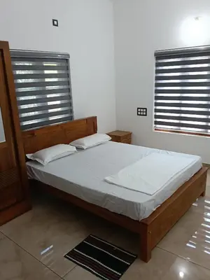 a bedroom with a bed and two windows at Anjali Holiday Home in Tindummal