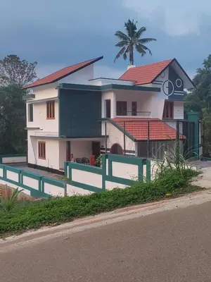 a house with a green fence in front of it at Anjali Holiday Home in Tindummal