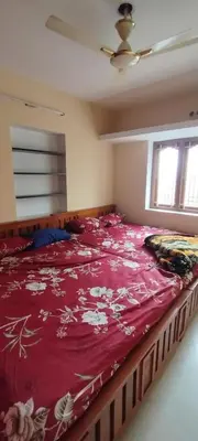 a large bed in a bedroom with a red blanket at sarathihomestay in Vālpārai