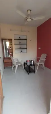 a living room with two white chairs and a table at sarathihomestay in Vālpārai
