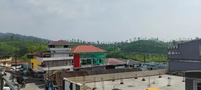 a group of buildings with a mountain in the background at sarathihomestay in Vālpārai