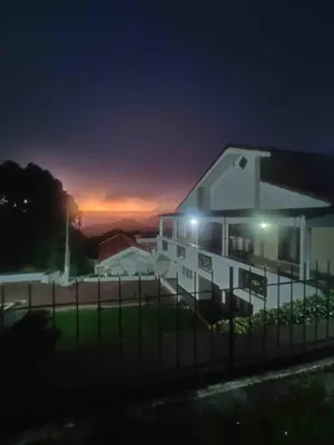 a building with a fence in front of it at night at Hill Side Cottage in Ooty