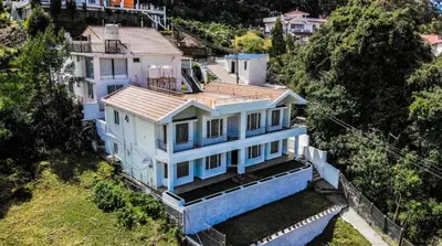 an aerial view of a large white house at Hill Side Cottage in Ooty