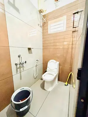a bathroom with a toilet and a shower and a bucket at MIRACLE INN Rajagiri in Cochin