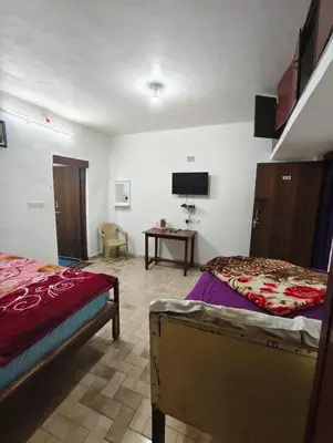 a bedroom with two beds and a table with a tv at MISTY cottage in Ooty