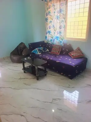 a living room with a purple couch and a table at Affordable home stay in Chāmrājnagar