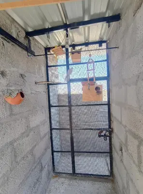 a bird cage in a brick wall with a window at Affordable home stay in Chāmrājnagar