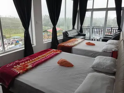 a room with three beds in front of a window at Alpha Inn in Vālpārai
