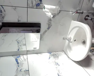 a white urinal in a bathroom with marble walls at Vaiga Heavens , 1 BHK Apartment in Guruvāyūr