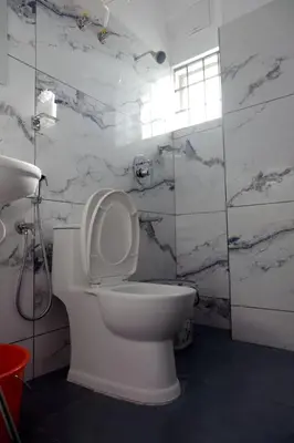 a white toilet in a bathroom with marble walls at Vaiga Heavens , 1 BHK Apartment in Guruvāyūr